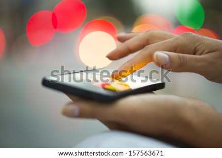 Mobile phone in a woman's hand, night, city ??of Light background, sms, message, e-mail 