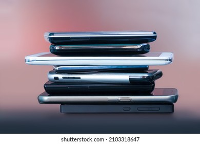 Mobile Phones In Stack On Table. Set Of Contemporary Smartphones, Side View. Wireless Communication Technology And Mobility Concept, Group Of Smartphones