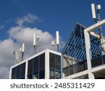 Mobile radio antennas on the roof of a modern office building with gables and spacious windows. Relentless to maintaining the communications network.