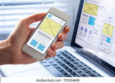 Mobile responsive website development with UI/UX front end designer previewing wireframe sketch layout design mockup on smartphone screen - Shutterstock ID 707654608