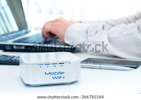 Mobile router device on the table and businessman with computer on background 