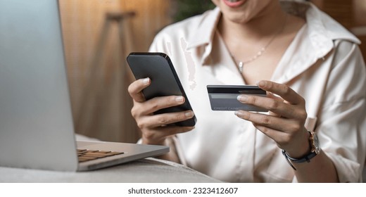Mobile Shopping. Cheerful Asian Woman Using Smartphone Shopping Online Holding Credit Card Making Payment Sitting At Sofa At Home. Internet Banking Application And E-Commerce - Shutterstock ID 2323412607