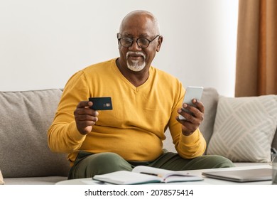 Mobile Shopping. Senior African Man Using Smartphone And Credit Card Making Payment Online Sitting On Couch Indoor. Male Customer Purchasing Something Via Phone. E-Commerce And Bank Application - Powered by Shutterstock