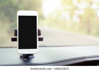 Mobile Smart Phone With Black Screen In Car Console Holder Stick Front. Insert Map Gps Navigation On The In The Background Of The Dashboard. Empty Screen For Text. Copy Space. Car Interior Details.