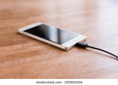 Mobile Smart Phone Charging On Wooden Desk