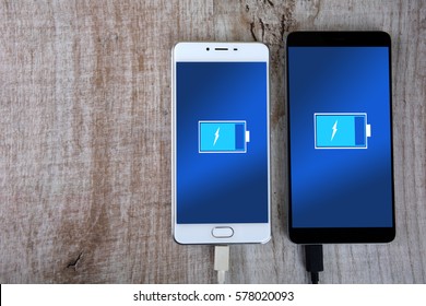 Mobile Smart Phones Charging On Wooden Desk