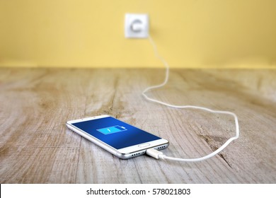 Mobile Smart Phones Charging On Wooden Desk