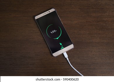 Mobile Smart Phones Charging On Wooden Desk