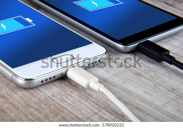 Mobile smart phones\
charging on wooden desk
