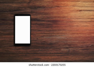 Mobile Smartphone With Blank Screen On Wood Desk Background With Copy Space. Top Down