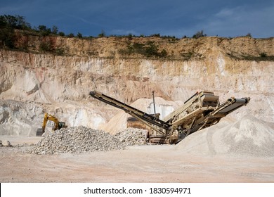 Mobile stone crushing machine with conveyor in a quarry. heavy machinery for crushing stones into gravel.