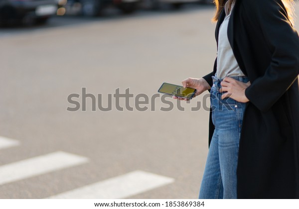 Mobile taxi service, modern technologies in the\
city. A woman uses her phone to search for a car. Hand with mobile\
app close-up