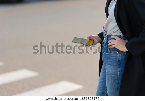 Mobile taxi service, modern technologies in the\
city. A woman uses her phone to search for a car. Hand with mobile\
app close-up