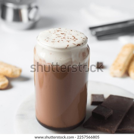 Mocha latte with whipped cream in a can shaped glass, iced mocha with foam and chocolate syrup