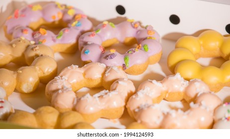 Mochinut, a hybrid of mochi and donuts. They are sticky in texture compared to a traditional donut. A box of dozen captured in bokeh with the focus on the donut to the back of the photo.