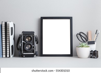 Mock with black frame and medium format camera, roll of films, books, office supplies. Photographer workspace.