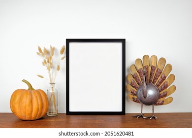 Mock Up Black Frame With Thanksgiving Turkey, Pumpkin And Autumn Decor On A Wood Shelf. Fall Concept. Portrait Frame Against A White Wall. Copy Space.