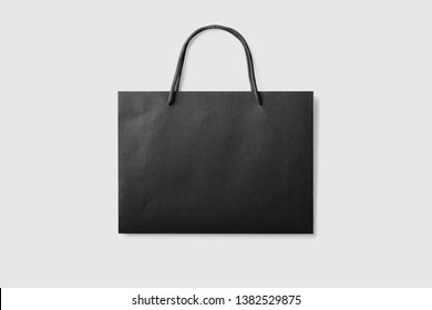 Mock up of a black paper shopping bag with handles on light grey background. High resolution.