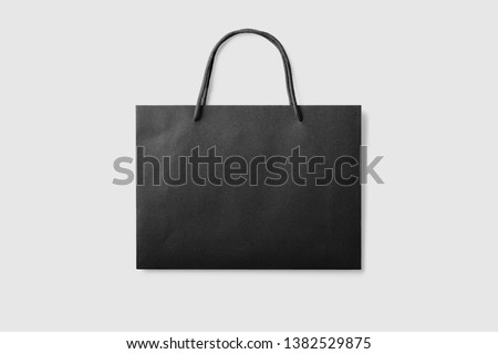 Mock up of a black paper shopping bag with handles on light grey background. High resolution.