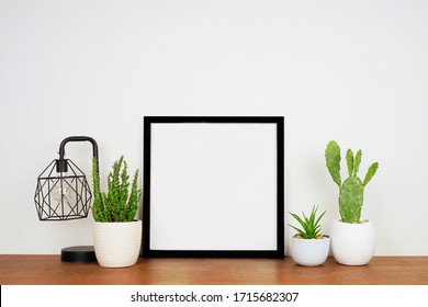 Mock up black square frame with home decor and potted plants. Wood shelf and wall. Copy space. - Shutterstock ID 1715682307