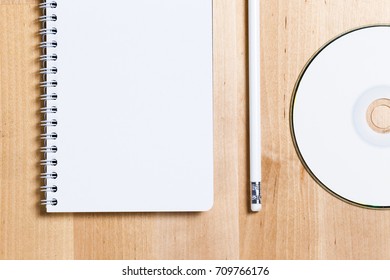 mock up of blank notebook, cd disc and badge on wooden office desk
