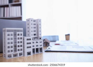 Mock up of building and documents placed on the desk of the agent in the real estate office to prepare for the customers who will come to see the property before deciding to buy the real estate. - Powered by Shutterstock