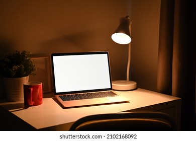Mock up computer laptop with warm light from lamp at night.