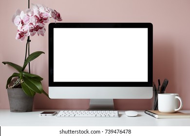 Mock up of creative desktop of female designer with nobody around: modern electronic gadgets, mouse, stationery accessories, notebook, cup and decorative plant against blank pink wall background