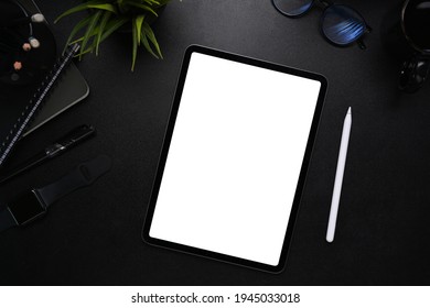 Mock up image of digital tablet with blank screen, stylus pen, smart watch, glasses and notebook on modern dark workplace. - Powered by Shutterstock