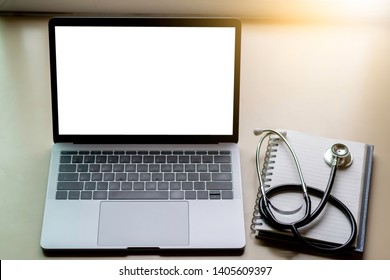 Mock up image of laptop computer with blank white screen, medical stethoscope and notebook on office desk. e health,telehealth,telemedicine or medical network concept.