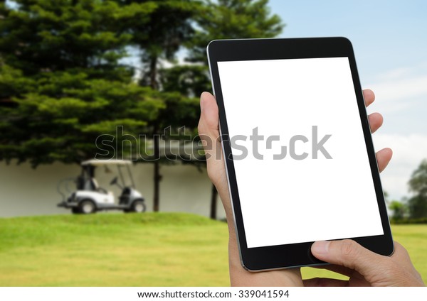 Mock up image, man hands\
holding digital tablet computer with blurred scene at golf court\
background.