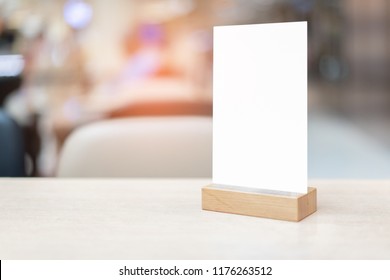 Mock Up Label The Blank Menu Frame In Bar Restaurant ,Stand For Booklets With White Sheet On Wooden Table Cafeteria Blurred Background