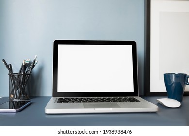 Mock up laptop computer with white screen, mobile phone, coffee up and stationery on dark blue table.