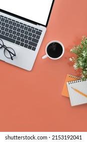 Mock Up Laptop With White Display, Coffee Cup And Notebook On Orange Background. Flay Lay.