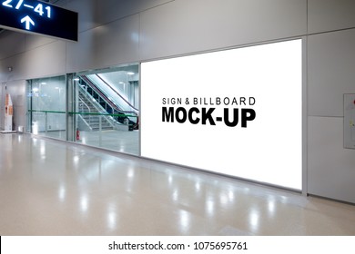 Mock Up Large Advertisement Signboard With Clipping Path Near The Sliding Door Entrance Into Airport Terminal Hall, Empty White Space For Advertising Or Information To Public Transportation.