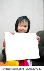 Mock Up Learning Book. Asian Child Girl Standing Holding To Show Working Book. Kid Sweet Smiling With Homework. Vertical Image. Children Aged 4-5 Years Old. Education At Home. Homeschool.