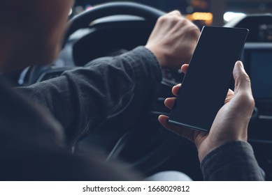 Mock Up Of Man Using Mobile Smart Phone Inside A Car. Driver Hand Holding Blank Black Screen Smartphone, Searching Address And Pin Location Via Map Navigator Application, Transportation Technology