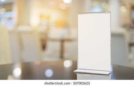 Mock up Menu frame  in Bar restaurant ,Stand for booklets with white sheets of paper acrylic tent card on wooden table on cafeteria  blurred background  - Shutterstock ID 507002623
