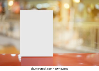 Mock Up Menu Frame  In Bar Restaurant ,Stand For Booklets With White Sheets Of Paper Acrylic Tent Card On Wooden Table On