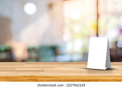 Mock up Menu frame on Table in Bar Restaurant Cafe. Stand Mock up Menu frame tent card blurred background design key visual layout. Empty wood table top with cafe restaurant interior blur background