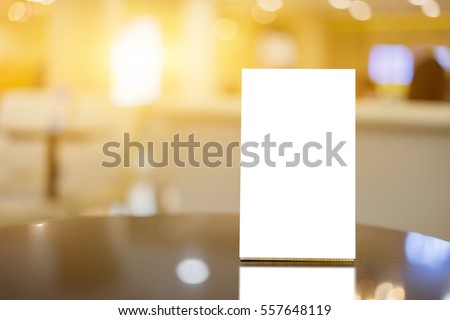 Mock up Menu frame on Table in Bar restaurant ,Stand for booklets with white sheets of paper acrylic tent card on cafeteria blurred background