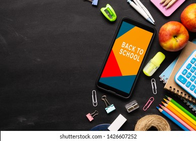 Mock up mobile phone for back to school background concept. School items on black chalkboard background with copy space, top view flat lay background.
