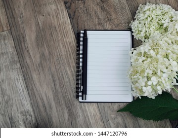 mock up ,notebook paper with white hydrangea flower on wooden background