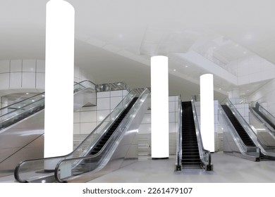 mock up out of home OOH; wide angle view of generic empty train station with escalators for advertising mockup display. Tall blank white pillars for easy poster placements