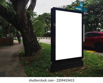 Mock Up Of An Outdoor Digital Bus Stop Ad In A Residential Neighbourhood, With A Car And Cyclist In The Background.