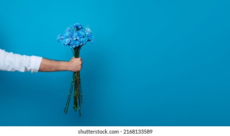 Mock Up Photo Of Male Hand With Fresh Bouquet Of Blue Flowers Isolated On Blue Background. Birthday. Women's Day. Valentine's Day. Holidays Presents.