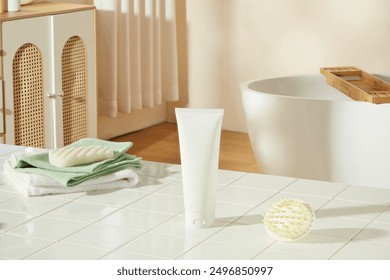 Mock up for promotional with a white cosmetic tube without label placed on white bathroom table, in back is some bathroom stocks like tub and cabinet. Empty space for advertising and adding text