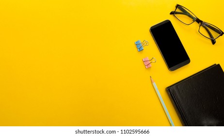 Mock up smartphone and office accessories on yellow background with copy space.view from above - Shutterstock ID 1102595666