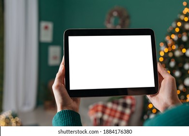 Mock up of a tablet in the hands of a girl against the background of a Christmas tree with a festive decor - Powered by Shutterstock