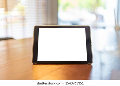 Mock Up Tablet Like IPad Stand On The Wooden Desk In Office Background With White Screen Clipping Path